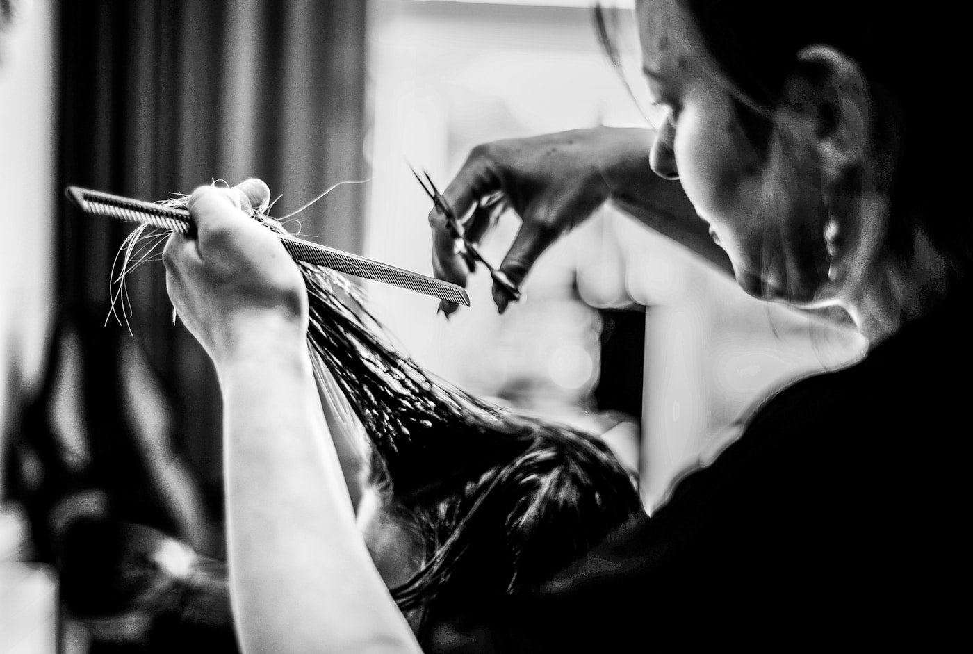Una profesional concentrada en el corte de cabello de su clienta
